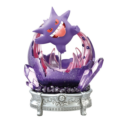 A decorative figure of Gengar from Pokémon, shown floating with a mischievous grin above a jagged purple base resembling a cracked geode. The display features translucent crystals, dark gem-like details, and rests on an ornate silver pedestal.